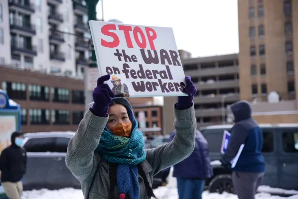 Woman with handmade sign reading 'Stop the War on Federal Workers'